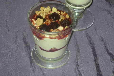 Dessert im Glas mit Kirschen, zerbröseltem Keks und Fruchtsauce.