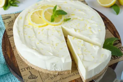 Cremige Philadelphia Torte mit Zitronenscheiben und Minze, ein Stück wurde bereits entnommen.