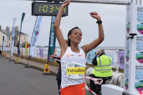 Victoire de Yehualaw, record semi marathon femme, franchissant la ligne d'arrivée avec les bras levés.