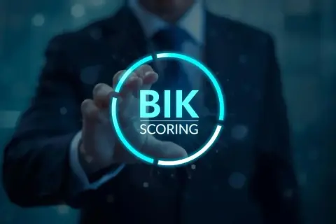 Dłoń w garniturze dotyka interfejsu, gdy bik aktualizuje dane. Widoczny napis "BIK SCORING" w neonowym okręgu.