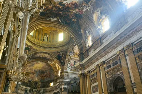 Interno della chiesa del Gesù, con affreschi barocchi sul soffitto, cupola e decorazioni dorate.