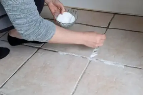 Application d'une pâte de bicarbonate et vinaigre pour nettoyer joint salle de bain.