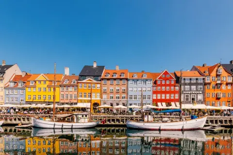 Bunte Häuser am Nyhavn, ein Kopenhagen must see. Boote spiegeln sich im Wasser.