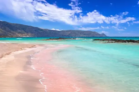 Różowa plaża z turkusową wodą i górami w tle – to jedna z najpiękniejszych plaż na świecie.