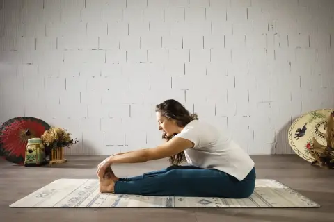 Mujer en postura de yoga Paschimottanasana, explorando el hatha significado de la calma y la conexión.