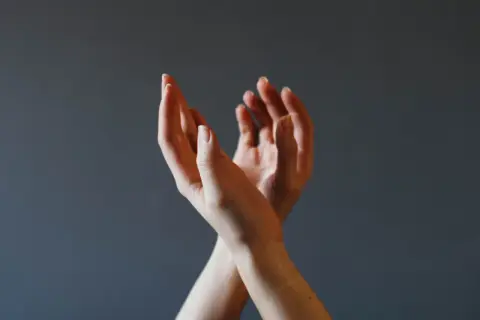Dłonie splecione w geście, który może symbolizować trudności w wyrażaniu emocji, ale też potencjał do rozwoju psychomotoryki.