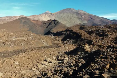 Paisaje volcánico árido visto desde el mirador de Samara, con montañas y conos de ceniza bajo un cielo azul.
