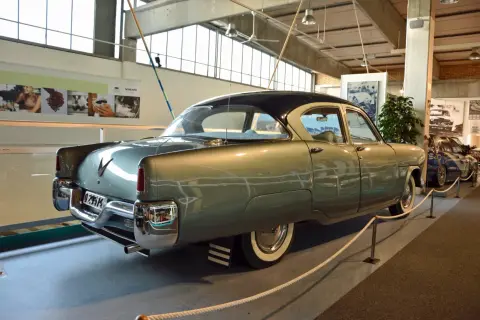 A vintage Volvo sedan, light green with a dark roof, is displayed indoors.