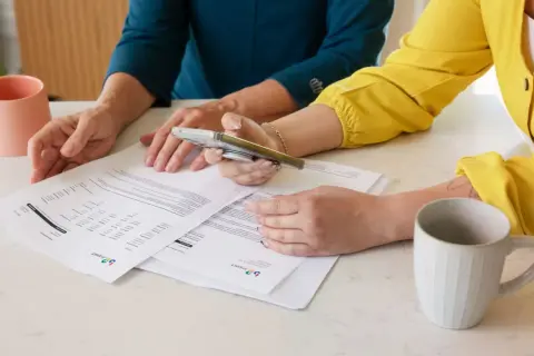 Dwie kobiety analizują dokumenty, być może dotyczące pełnomocnictwa szczególnego.