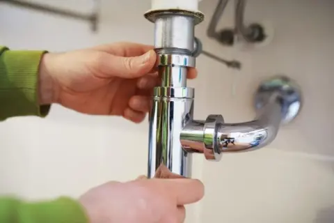 Mains pour démonter un siphon de lavabo, une étape clé pour savoir comment déboucher.