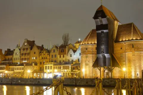 Gdańsk nocą, z Żurawiem i kamienicami odbijającymi się w wodzie.