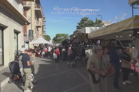 Festa San Crispino a Porto Sant'Elpidio: bancarelle affollate, gente che passeggia e acquista sotto un cielo azzurro.