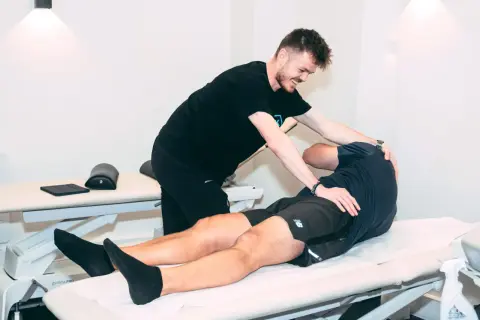 Un ostéopathe pratique un ostéo massage sur un patient allongé sur une table de soin, soulageant ses tensions musculaires.