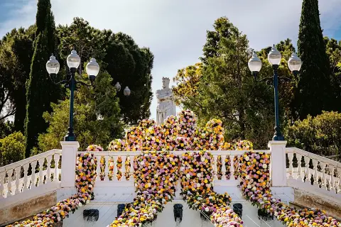 Escaleras adornadas con miles de flores vibrantes, donde zgz florece en un espectáculo de color. Una estatua real preside la escena.