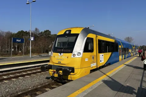 Pociąg TLK z żółto-niebieskimi pasami na stacji Hel, gotowy do podróży przez malownicze wydmy.