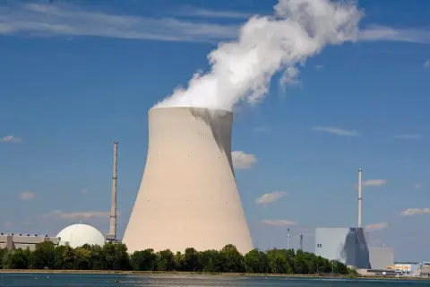 Chłodnia kominowa i budynki elektrowni atomowych w Niemczech na tle błękitnego nieba.