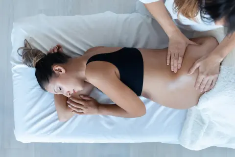 Une femme enceinte reçoit un massage du dos. Apprenez comment masser son périnée pour une préparation à l'accouchement en douceur.