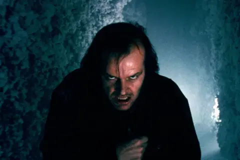 Jack Nicholson z przerażającą miną w ciemnym korytarzu.