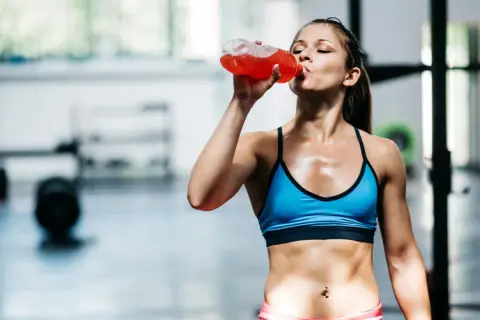 Eine Frau trinkt nach dem Training ein isotonisches Getränk. Es hilft, den Flüssigkeits- und Elektrolythaushalt auszugleichen.