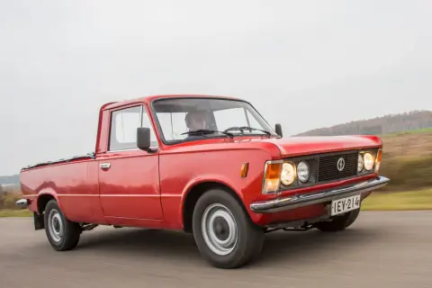 Czerwony fiat 125p pickup w ruchu, z kierowcą za kierownicą. Klasyk na drodze.