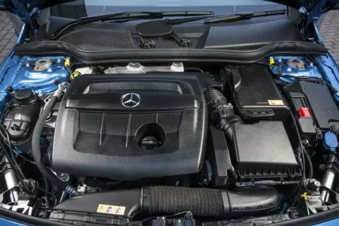 Motor de un Mercedes Clase A 180 gasolina, con su tapa negra y el logo de la estrella.