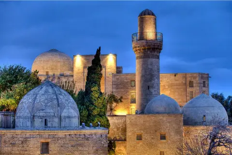 Meczet z minaretem i kopułami w Baku, symbol azerbejdżańskiej religii, oświetlony nocą.