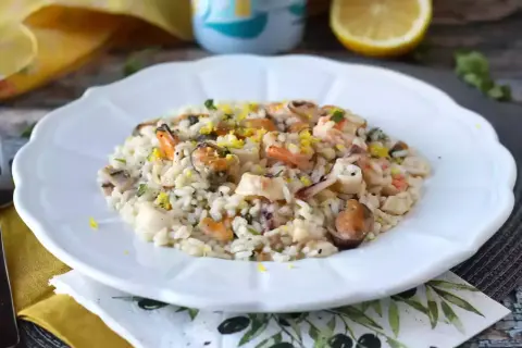 Un délicieux risotto fruits de mer crémeux, garni de zestes de citron et de persil frais.