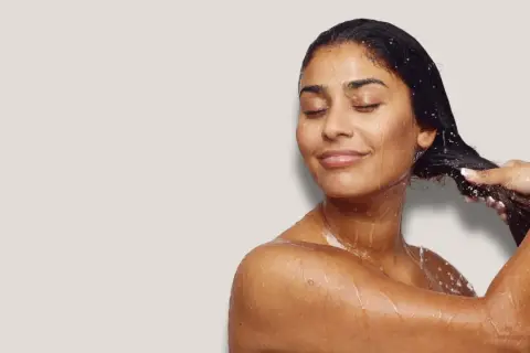 Frau mit geschlossenen Augen, die sich die nassen Haare wäscht. Sie genießt die Pflege, als würde sie ihre Haare nur mit Conditioner waschen.