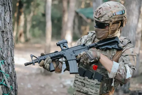 Jugador de fps airsoft con casco y rifle táctico, listo para la acción en un bosque.