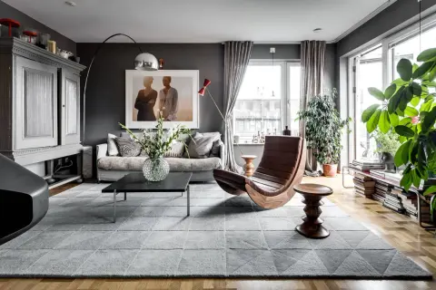 Stilvolles Wohnzimmer in Grau mit gemütlicher Couch, Design-Sessel und viel Grün. Tolle wohnzimmer grau ideen für ein modernes Zuhause.