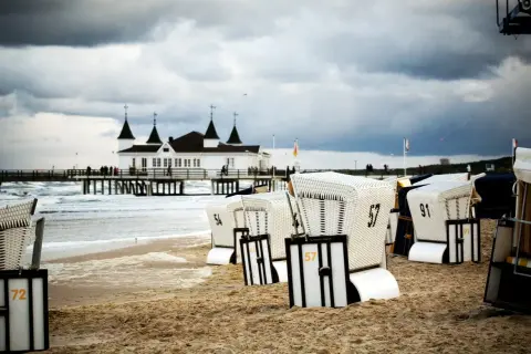 Strandkörbe am Ostseestrand mit Pier und Gebäude im Hintergrund. Perfekte ausflugsziele ostsee bei schlechtem wetter, um dem Wind zu trotzen.