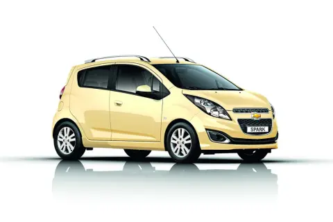 Żółty Chevrolet Spark, jeden z popularnych chevrolet modele, prezentuje się na białym tle.