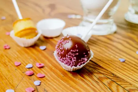 Schokoladen-Cake-Pops mit rosa Zuckerstreuseln und ein ungefüllter Cake Pop, bereit für ein einfaches cake pops rezept.