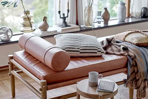 Un cómodo espacio de meditación con un banco de cuero, cojines texturizados y mantas cálidas.