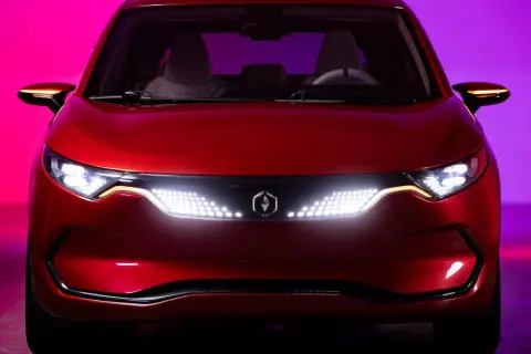 Czerwone izera auto z nowoczesnymi światłami LED i logo producenta na tle fioletowo-różowego oświetlenia.