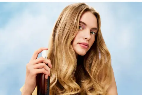 Mujer rubia aplica bruma en su pelo, logrando un brillo radiante.