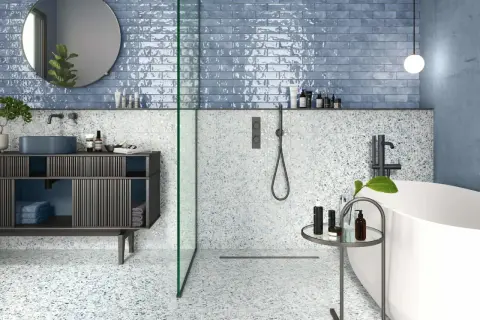 Salle de bain moderne avec carrelage mural bleu brillant et sol terrazzo. La taille du carrelage mural salle de bain est rectangulaire, créant un effet de profondeur.