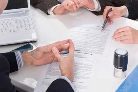 Manos revisando documentos, uno de ellos es un **hipotecante no deudor**, junto a un sello y portátil.