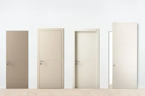 Quattro tipi di porte moderne, con maniglie in metallo e finiture diverse, su un pavimento in legno chiaro.