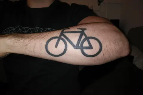 Schwarzes Fahrrad-Tattoo auf einem behaarten Arm. Ein Symbol für die Liebe zum Radfahren nach dem Tattoo.