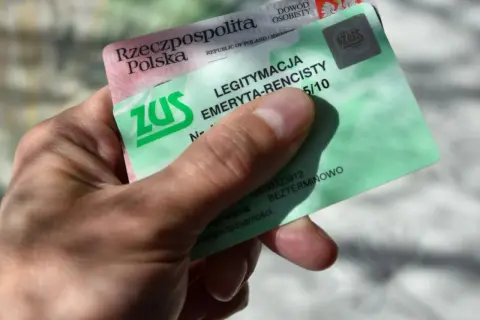 Dłoń trzyma zieloną legitymację emeryta-rencisty ZUS. Dokument potwierdza uprawnienia do świadczeń.