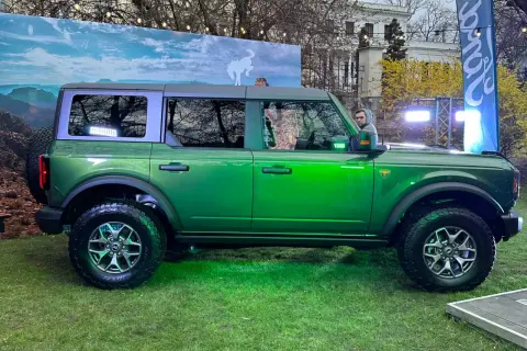 Zielony Ford Bronco prezentuje się imponująco na tle krajobrazu z dzikim koniem.