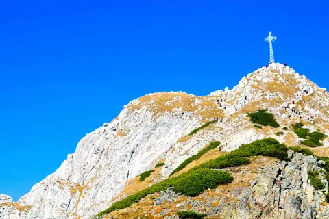 Giewont z Zakopanego, majestatyczny szczyt z krzyżem, na który wspina się grupa turystów.