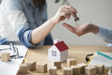 Mani che si scambiano una chiave con un ciondolo a forma di casa. Dopo lo sfratto devo pagare per questo nuovo inizio.