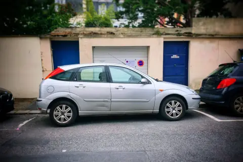 Une voiture argentée est garée devant un garage. Une autre voiture est garée juste derrière. Peut-on se garer devant son garage ?
