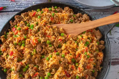 Herzhafte hackfleisch reis pfanne mit Erbsen und Paprika, garniert mit Chilischoten. Ein köstliches Gericht für die ganze Familie.