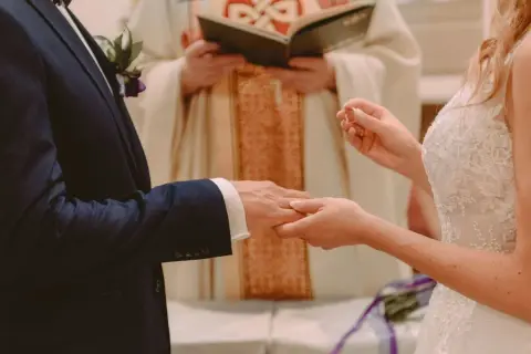 Para ślubna wymienia obrączki. Czy sakrament bierzmowania jest potrzebny do ślubu? Kapłan błogosławi parę.