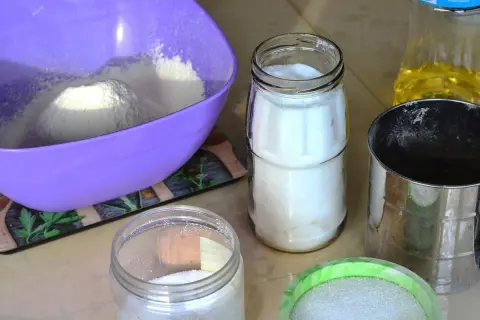 Filiżanki z mąką, cukrem i olejem na kuchennym blacie.