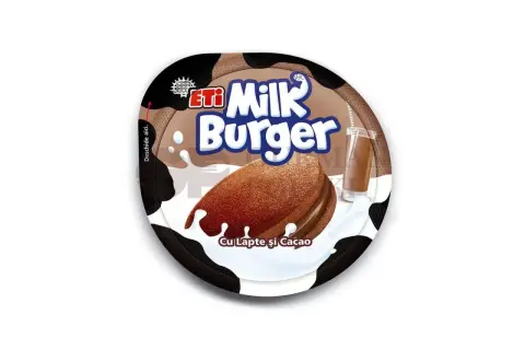 Czekoladowe ciastko Milk Burger z kremem, oblane mlekiem, obok szklanki mleka czekoladowego.