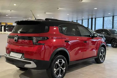 Błyszczący czerwony Citroën C3 Aircross z czarnym dachem stoi w salonie.